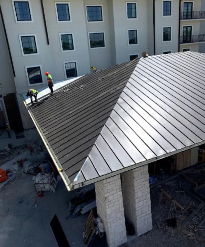 Crew installing standing seam metal roof panels on a commercial project in Wood River